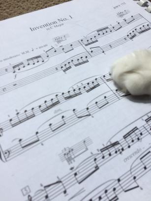 Cat paw on sheet music for Bach Invention 1